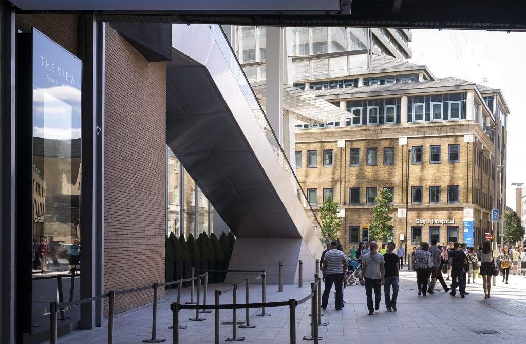 A group of people walking down a sidewalk in front of a building.