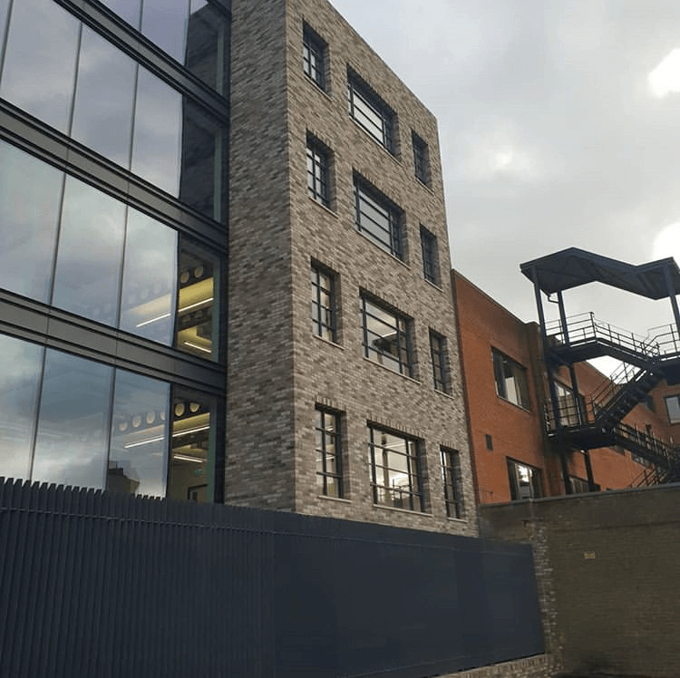 A modern building with large glass windows adjacent to an MCPV021 structure under a cloudy sky.
