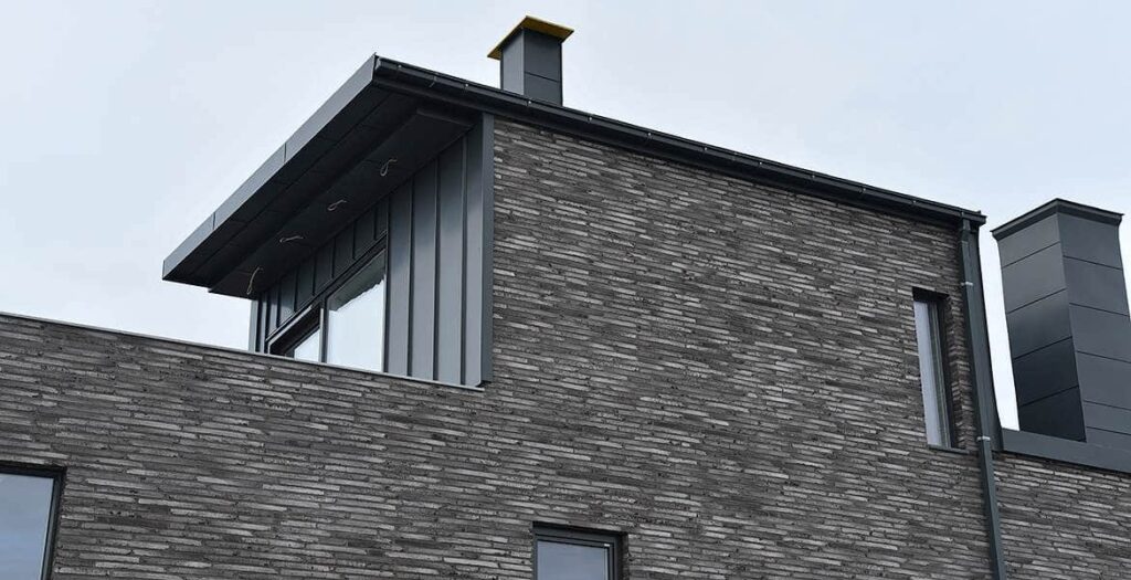 A grey MCPN033 building with a black chimney.
