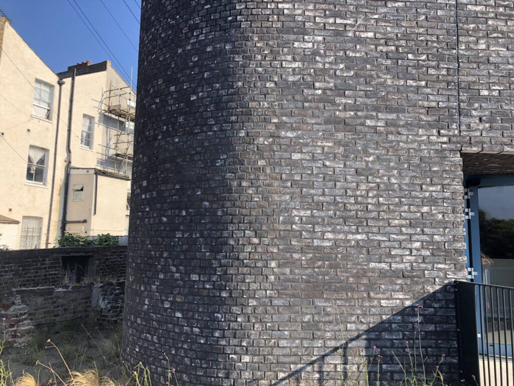 A curved, textured MCPV069 wall in an urban setting with residential buildings visible in the background.
