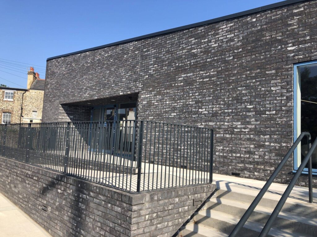 Modern brick building with large MCPV069 window and metal railing on a sunny day.