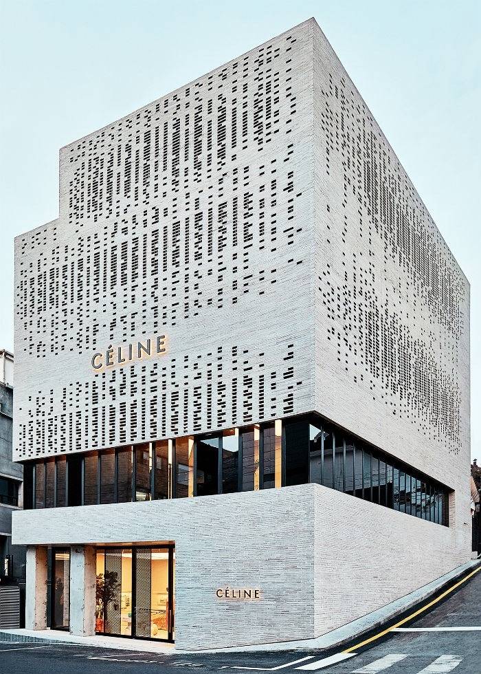 Modern MCPV352 fashion boutique exterior with geometric perforated facade, prominently displaying the brand logo, set on a street corner.