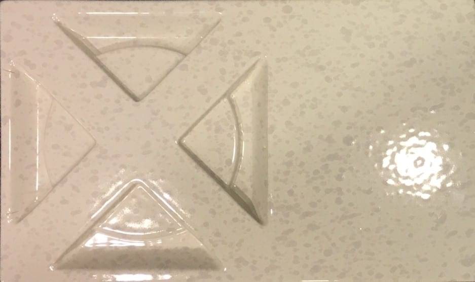 A white tile with a cross design on it.