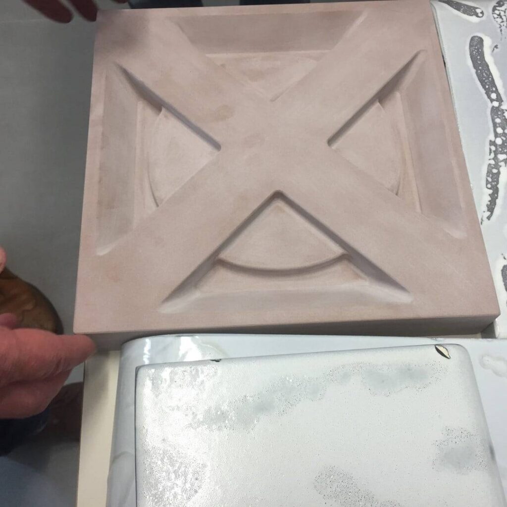 A person is holding a piece of terra cotta on a table.