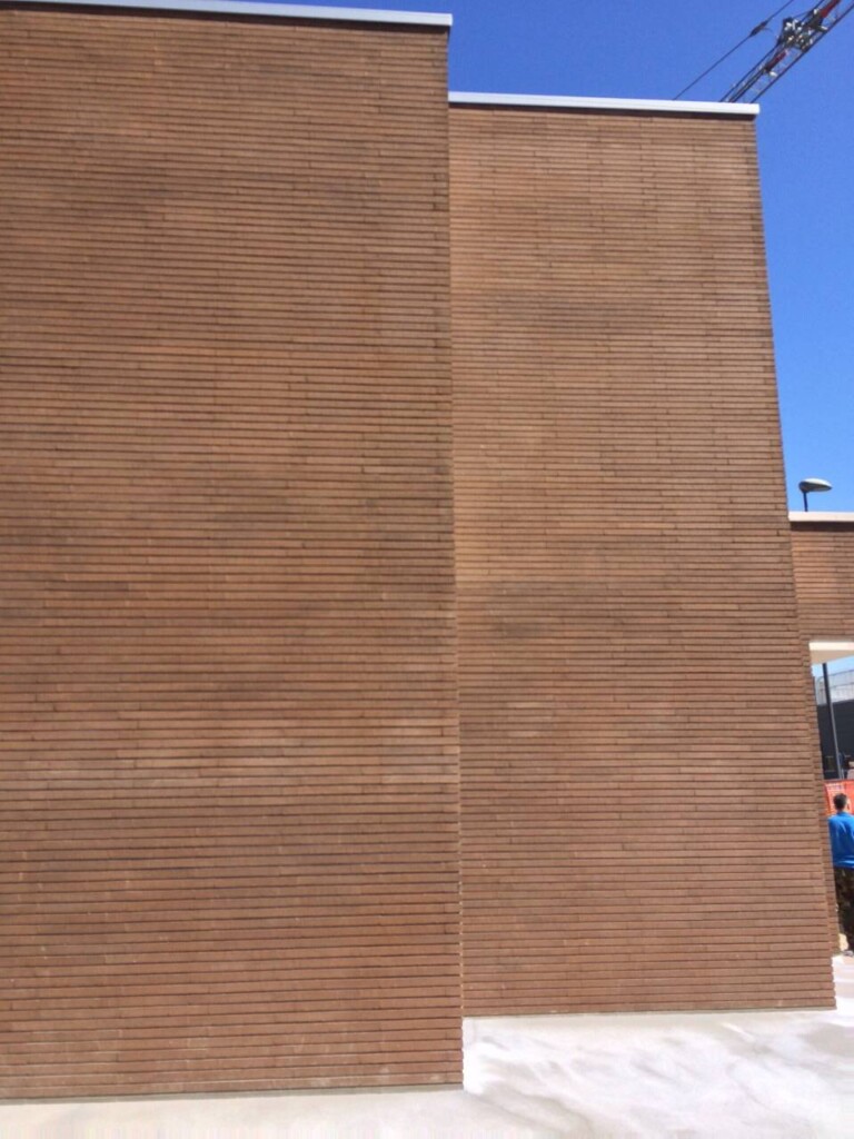 A tall, plain rectangular building with horizontal linear patterns on its facade against a clear blue sky, resembling the MCPV308.