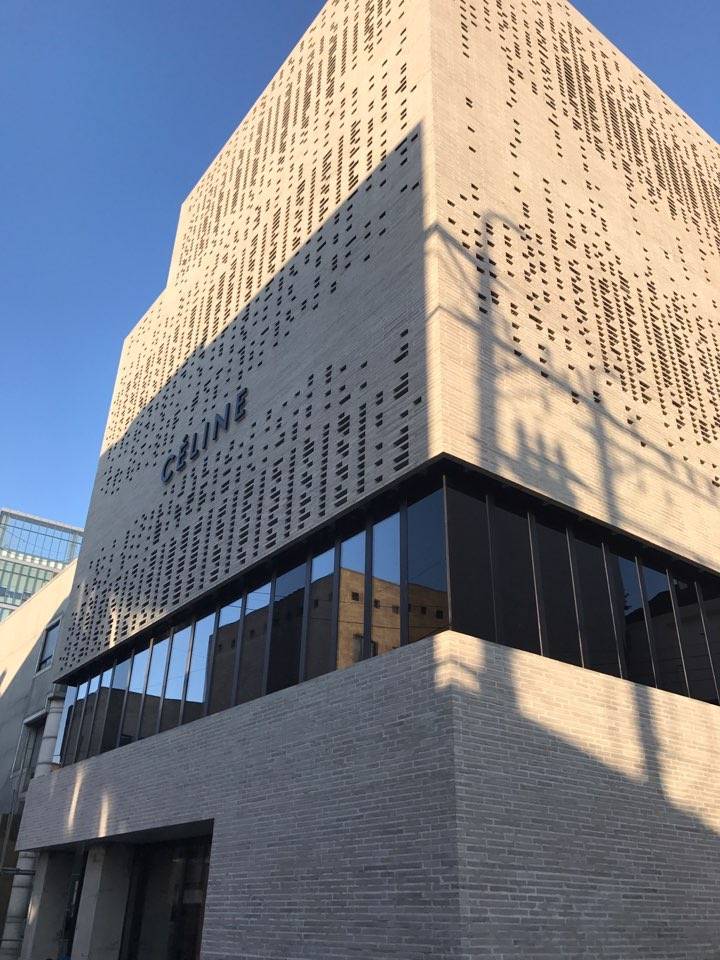 Modern building with perforated facade featuring large windows and the word 