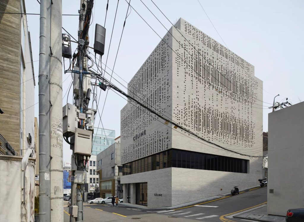 Modern building with perforated facade on an urban street corner, featuring contrasting textures