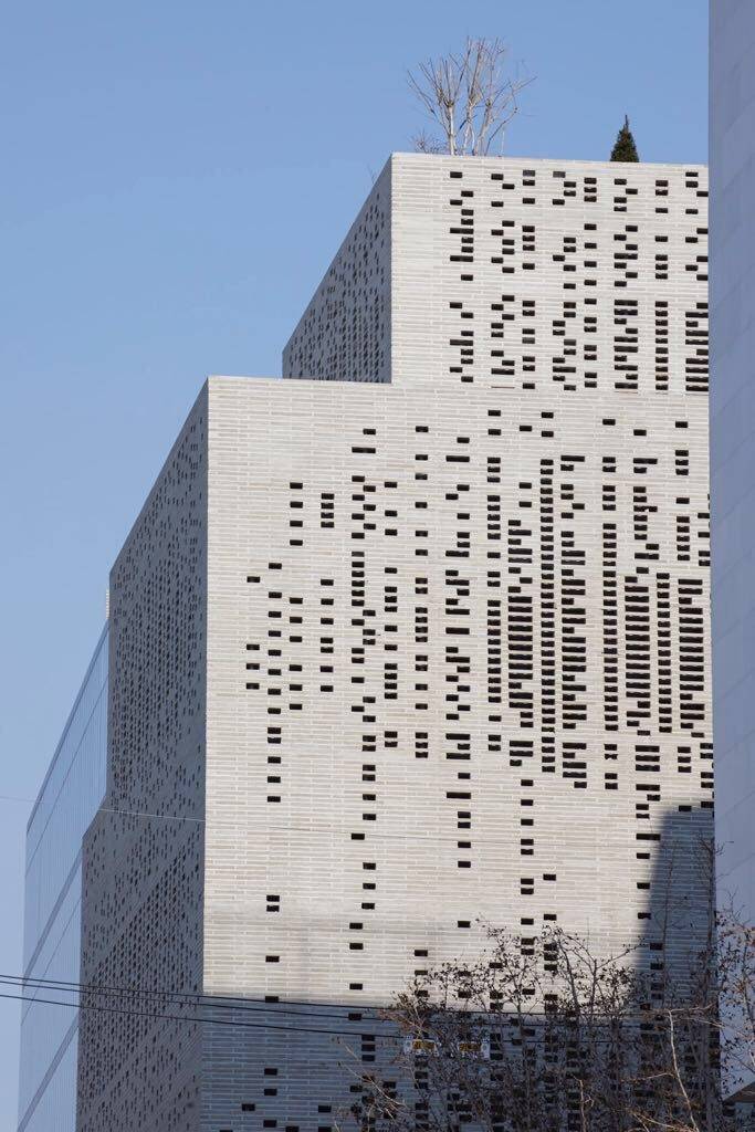 Modern geometric buildings with a pattern of square windows against a clear sky.