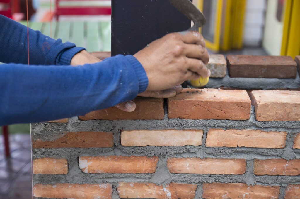 the worker is using the trowel for masoning the brick