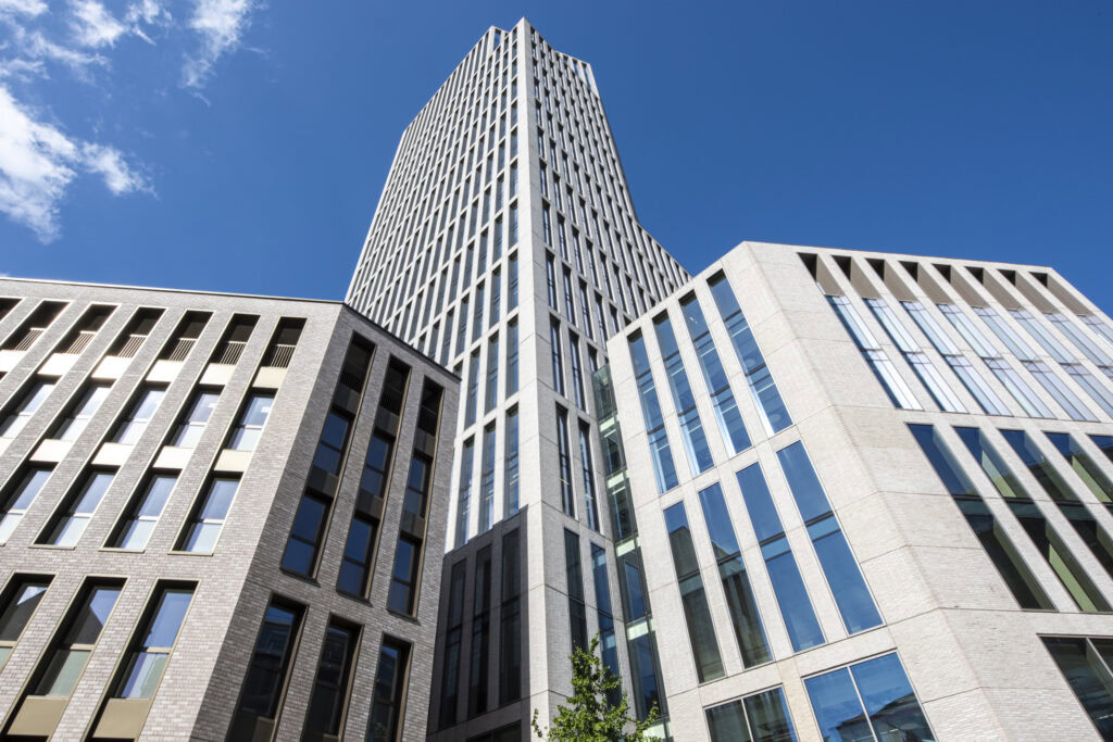 Modern high-rise office buildings with geometric facades under a clear blue sky.