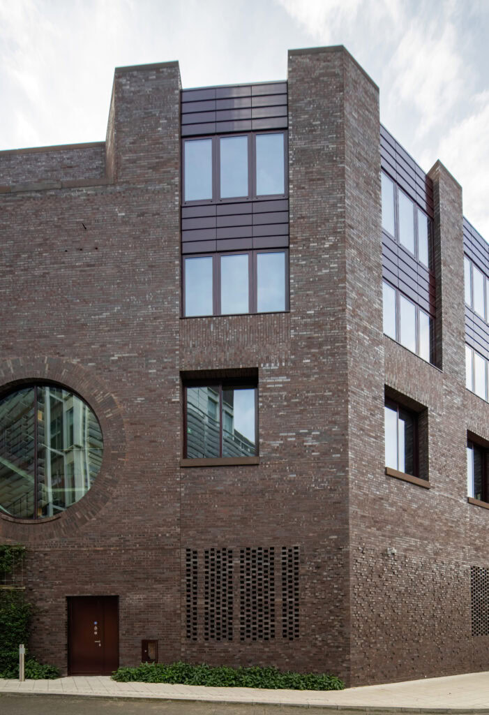 Modern brick building with large windows, featuring a symmetrical design & a reflective glass entry