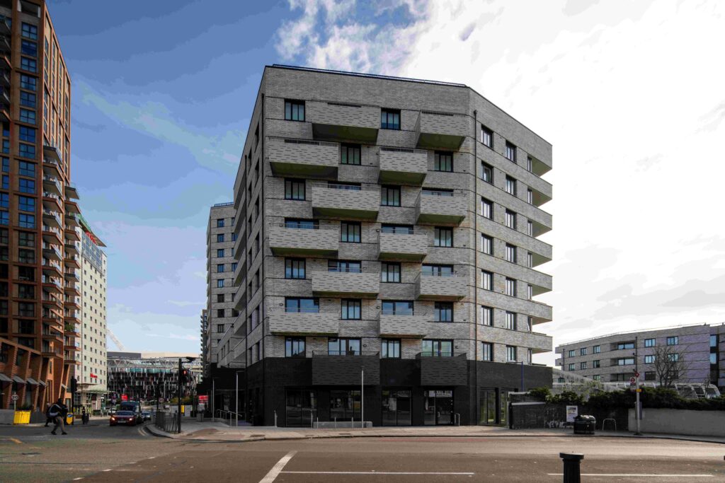 A modern, multi-story MCPV175 with a gray and black exterior stands at a street intersection.